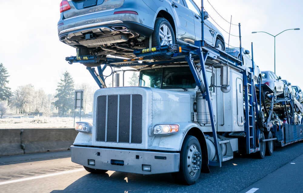 White Peterbilt car hauler loaded with SUVs on a winter highway